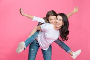 Happy mother piggybacking adorable little daughter smiling at camera-img-blog