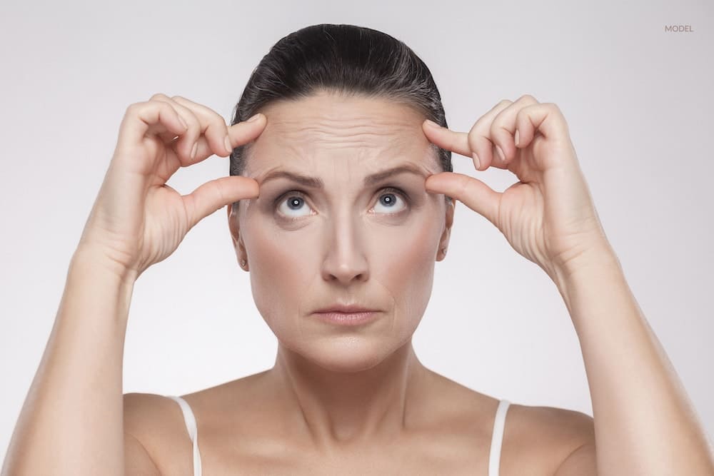 Women scrunching up her forehead, wondering if she could benefit from a cosmetic anti-aging treatment.